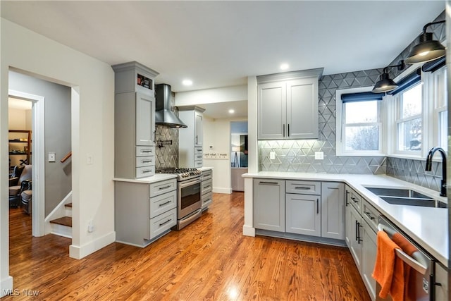 kitchen featuring gray cabinetry, appliances with stainless steel finishes, sink, and wall chimney range hood