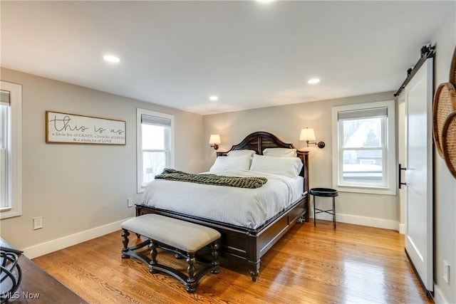 bedroom with multiple windows, a barn door, and light wood-type flooring