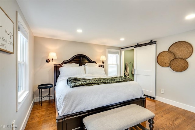 bedroom with wood-type flooring and a barn door