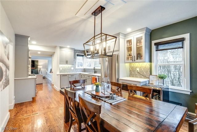 dining area with an inviting chandelier, a healthy amount of sunlight, sink, and light hardwood / wood-style floors