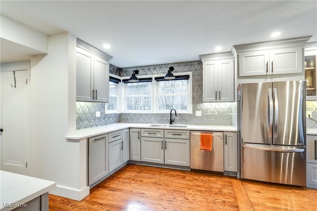 kitchen featuring sink, tasteful backsplash, appliances with stainless steel finishes, gray cabinets, and light hardwood / wood-style floors