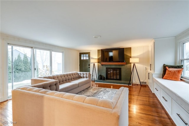 living room featuring a wealth of natural light, a brick fireplace, and hardwood / wood-style floors