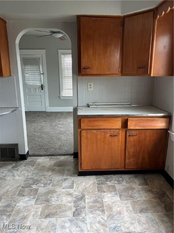 kitchen featuring ceiling fan, light colored carpet, and decorative backsplash