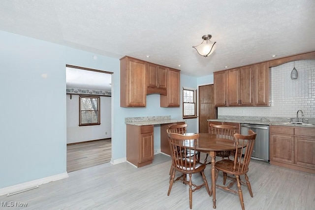 kitchen with tasteful backsplash, sink, stainless steel dishwasher, a textured ceiling, and light hardwood / wood-style flooring