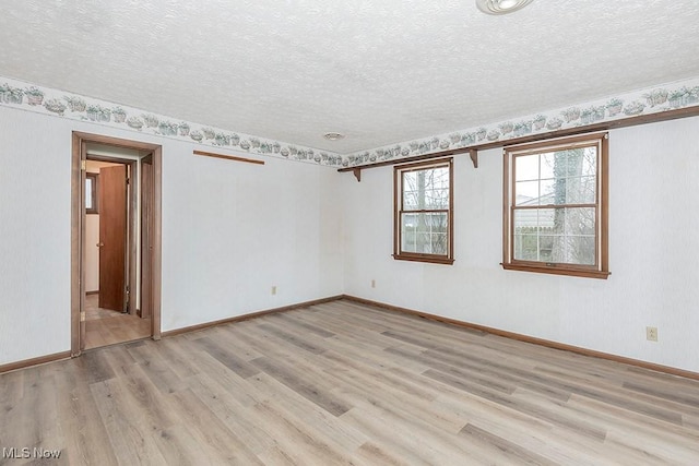 spare room with a textured ceiling and light wood-type flooring