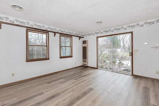 spare room featuring a textured ceiling and light hardwood / wood-style floors