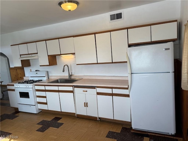 kitchen with white cabinetry, sink, white appliances, and light parquet flooring