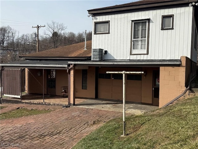 exterior space featuring a yard, a garage, and central AC