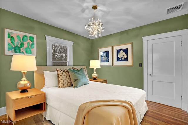 bedroom with a chandelier and hardwood / wood-style floors