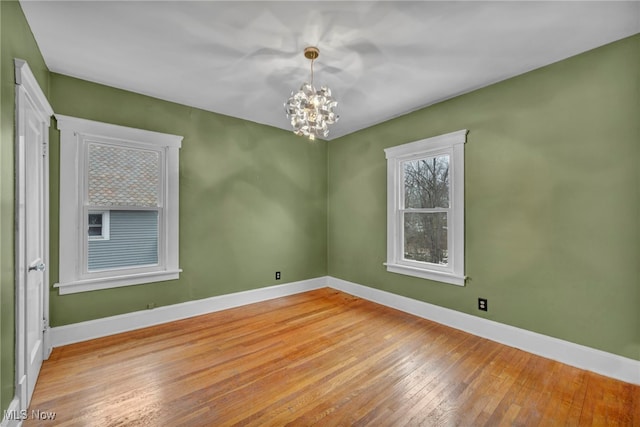 spare room featuring a chandelier and light hardwood / wood-style flooring