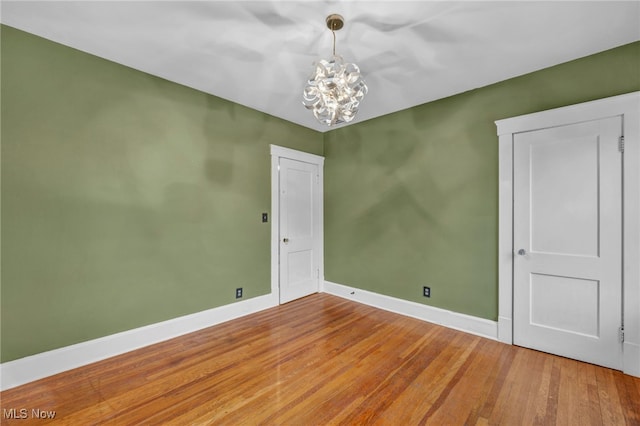 empty room with hardwood / wood-style flooring and a chandelier