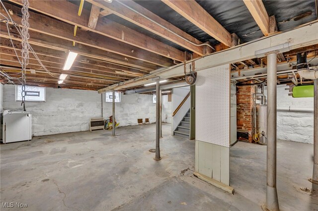 basement featuring water heater and refrigerator