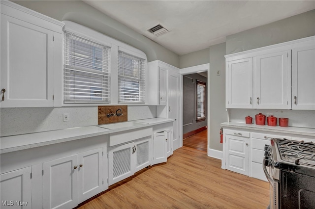 kitchen featuring light wood-type flooring, gas range, sink, and white cabinets