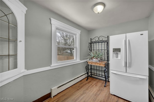 kitchen featuring white fridge with ice dispenser, baseboard heating, and light hardwood / wood-style floors