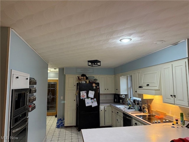 kitchen with tasteful backsplash, white cabinetry, black appliances, sink, and kitchen peninsula