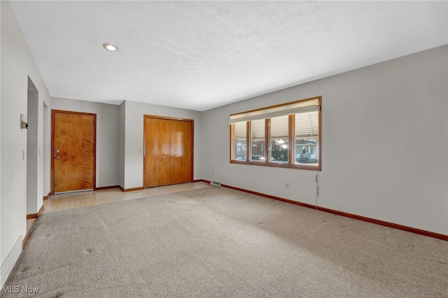 unfurnished bedroom with a closet, light carpet, and a textured ceiling