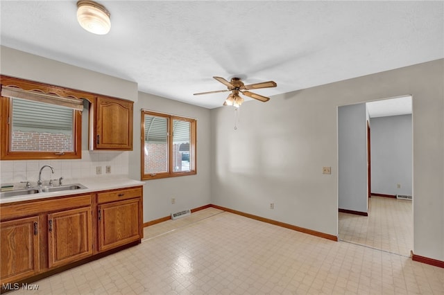 kitchen featuring tasteful backsplash, sink, a textured ceiling, and ceiling fan