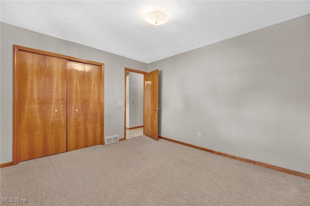 unfurnished bedroom featuring carpet flooring, a closet, and a textured ceiling