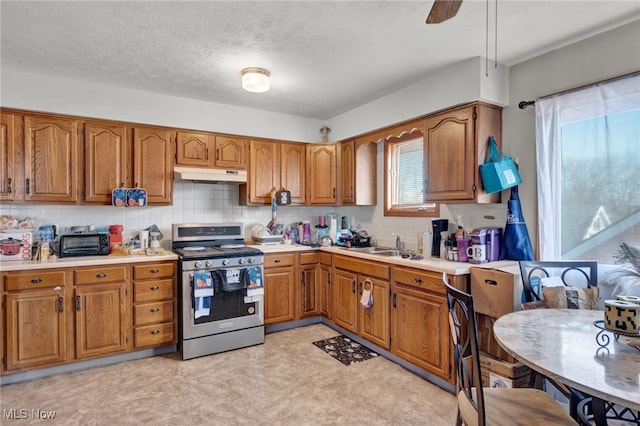 kitchen with sink, ceiling fan, tasteful backsplash, gas stove, and a textured ceiling