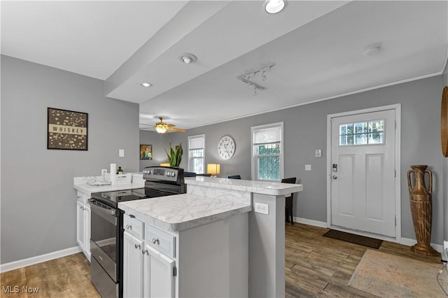 kitchen featuring white cabinets, hardwood / wood-style flooring, electric range, and kitchen peninsula