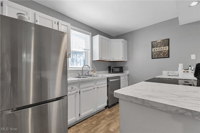 kitchen with appliances with stainless steel finishes, sink, and white cabinets