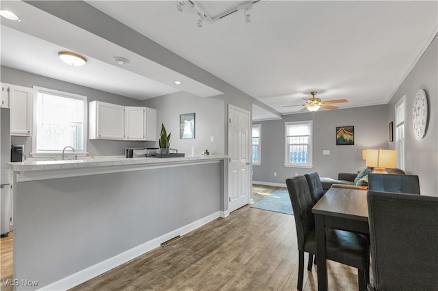 kitchen with rail lighting, white cabinetry, light hardwood / wood-style flooring, kitchen peninsula, and ceiling fan