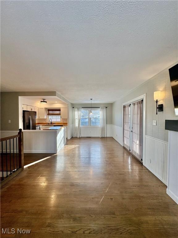 unfurnished living room featuring dark hardwood / wood-style floors, sink, and a textured ceiling