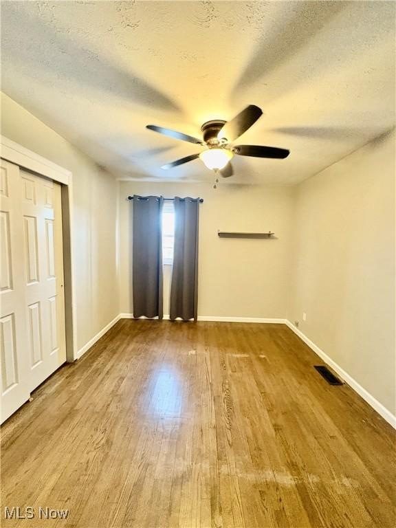 unfurnished bedroom with ceiling fan, wood-type flooring, and a textured ceiling