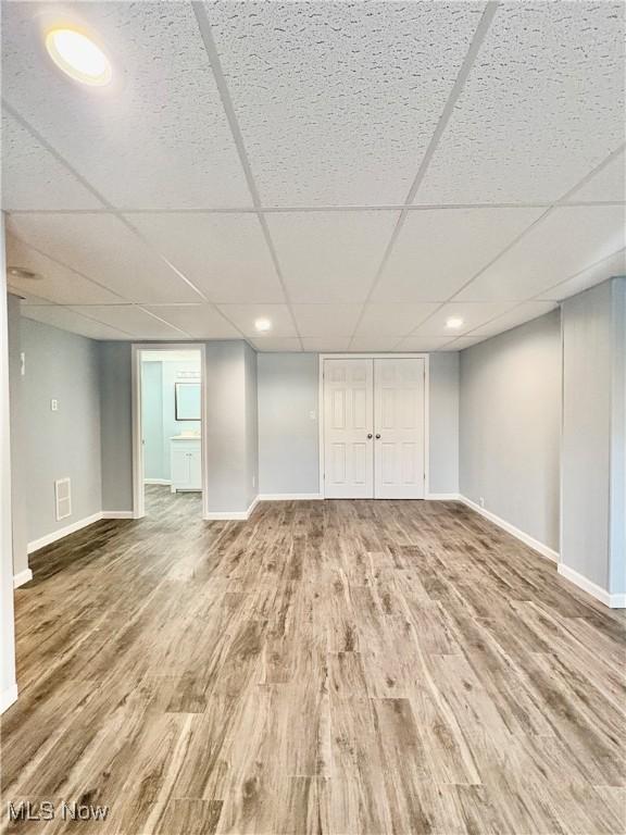 basement with wood-type flooring and a paneled ceiling