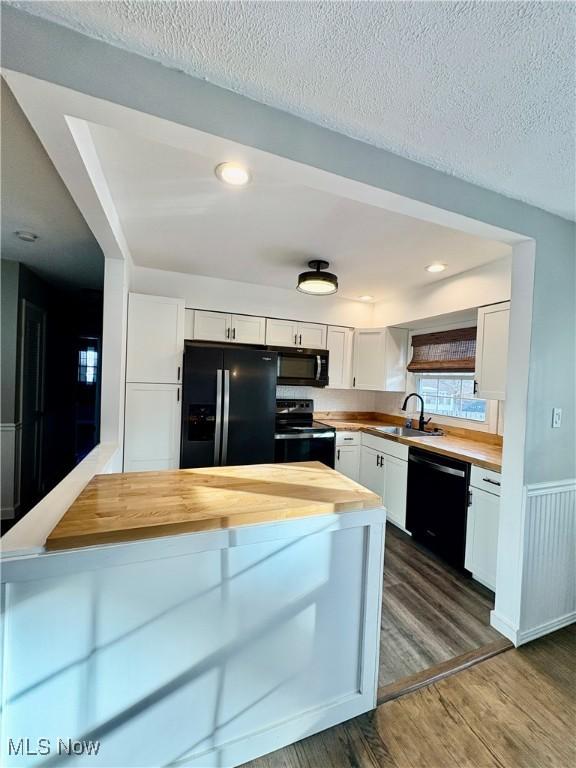 kitchen featuring white cabinetry, sink, wooden counters, black appliances, and dark wood-type flooring