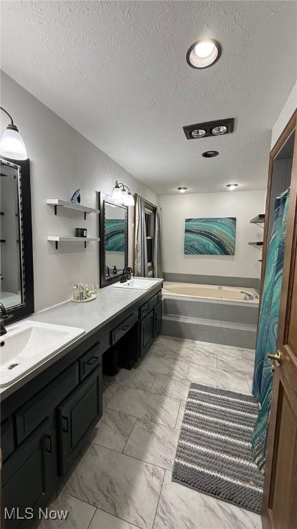 bathroom with vanity, tiled bath, and a textured ceiling