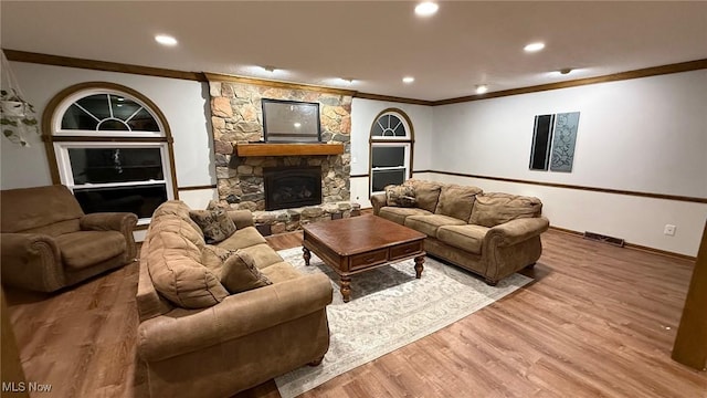 living room featuring crown molding, a stone fireplace, and hardwood / wood-style flooring