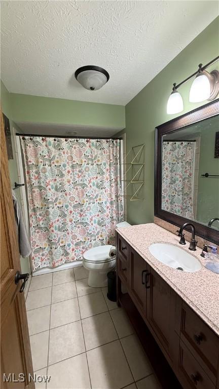 bathroom featuring vanity, toilet, tile patterned flooring, and a textured ceiling