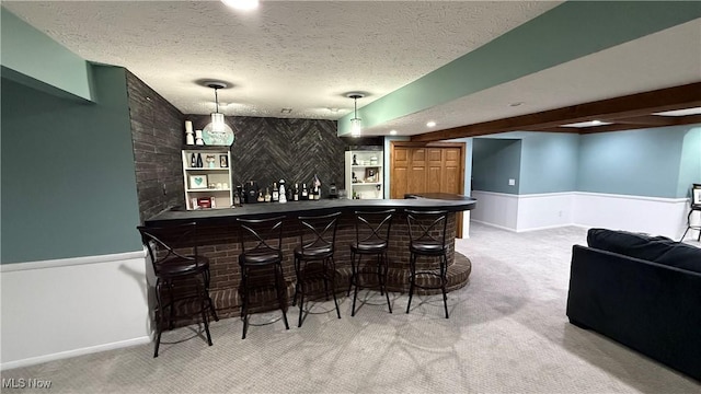 bar with beam ceiling, pendant lighting, light colored carpet, and a textured ceiling