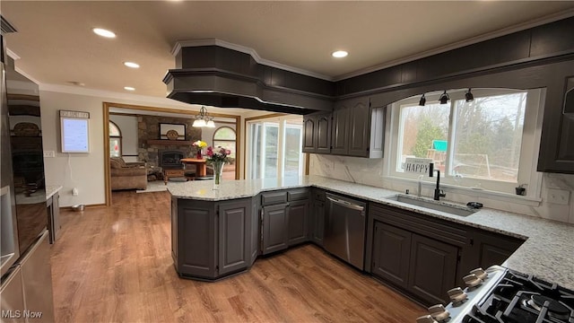 kitchen featuring a stone fireplace, sink, wood-type flooring, dishwasher, and light stone countertops