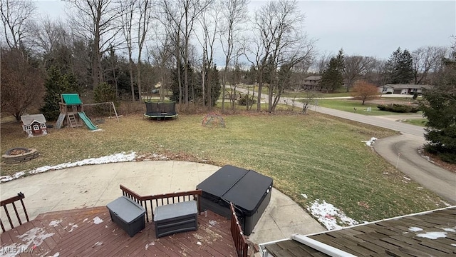 view of yard featuring a playground, a wooden deck, and a trampoline