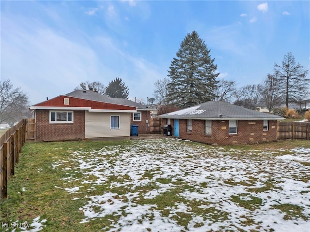 snow covered house featuring a yard