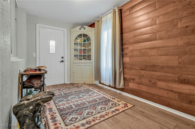 entryway featuring wood-type flooring and rustic walls