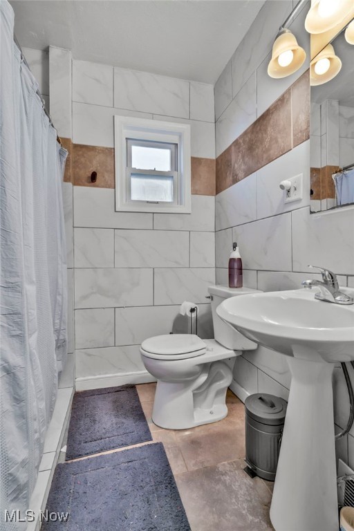 bathroom with tile walls, a shower with curtain, and toilet