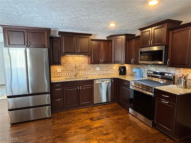 kitchen featuring dark hardwood / wood-style floors, tasteful backsplash, sink, light stone counters, and stainless steel appliances