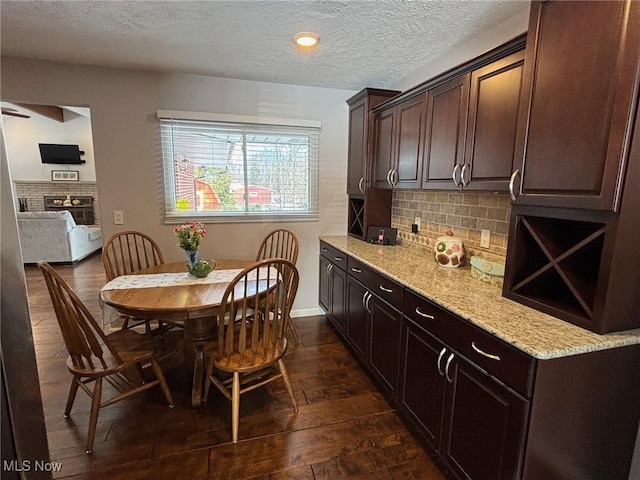 kitchen featuring dark wood-type flooring, tasteful backsplash, light stone counters, and dark brown cabinets