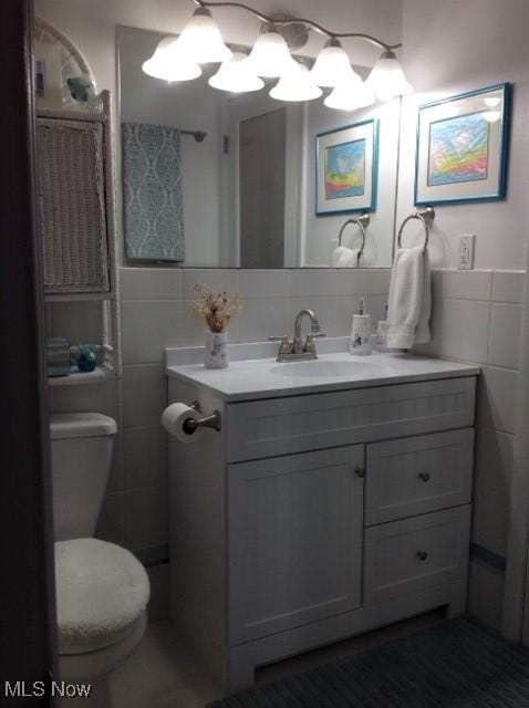 bathroom featuring tile walls, vanity, and toilet