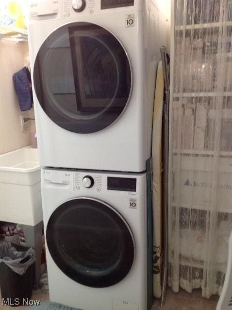 clothes washing area with stacked washer / drying machine and sink