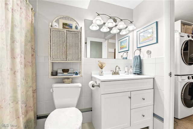 bathroom featuring vanity, stacked washer / drying machine, tile walls, and toilet