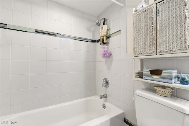 bathroom featuring tiled shower / bath combo and toilet