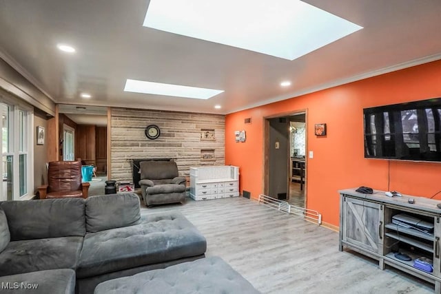 living room featuring ornamental molding, hardwood / wood-style floors, wood walls, and a skylight