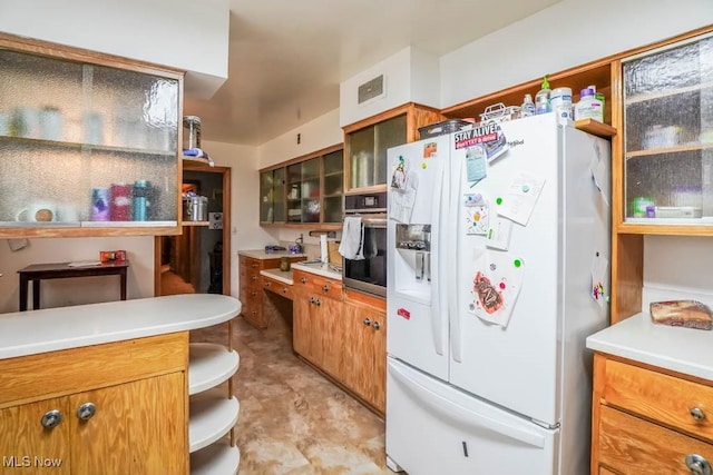 kitchen featuring stainless steel oven and white refrigerator with ice dispenser