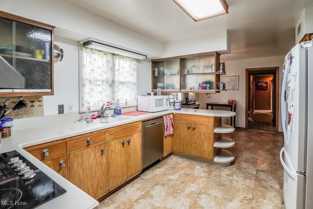 kitchen with tasteful backsplash, sink, white appliances, and kitchen peninsula