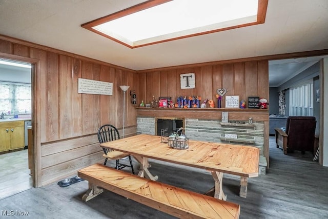 dining area with a skylight, wooden walls, and dark hardwood / wood-style flooring