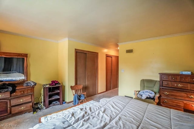 bedroom featuring ornamental molding, light carpet, and two closets